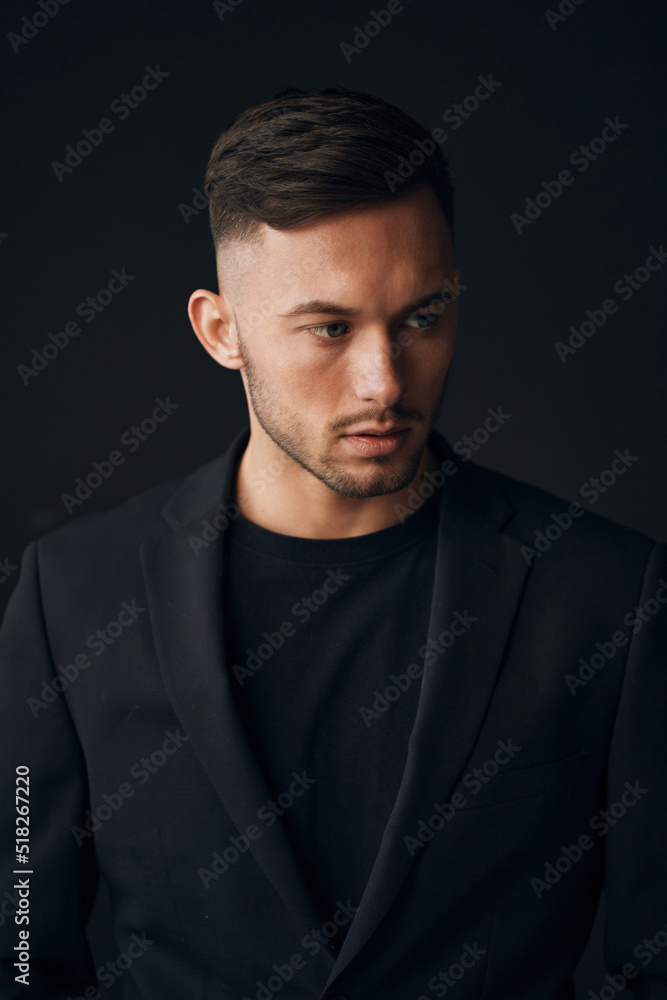 Modelling snapshots. Narcissistic self-confident tanned attractive handsome man in classic suit jacket looks aside posing isolated in over black studio background. Fashion offer. Copy space for ad Modelling snapshots. Narcissistic self-confident tanned attractive handsome man in classic suit jacket looks aside posing isolated in over black studio background. Fashion offer. Copy space for ad