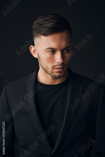 Modelling snapshots. Narcissistic self-confident tanned attractive handsome man in classic suit jacket looks aside posing isolated in over black studio background. Fashion offer. Copy space for ad