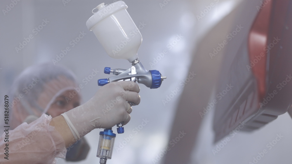 Painting vehicle parts at car service workshop. Car manufacturing factory. Auto painter spraying red paint on car door in special booth Painting vehicle parts at car service workshop. Car manufacturing factory. Auto painter spraying red paint on car door in special booth