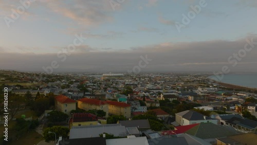Forwards fly above street in residential borough. Revealing panoramic view of city at sea coast. Port Elisabeth, South Africa