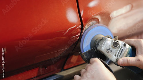 Car body panel repairing on the garage, car door panel dent removing. Auto repairman grinding automobile body. Accident car body repair on the garage