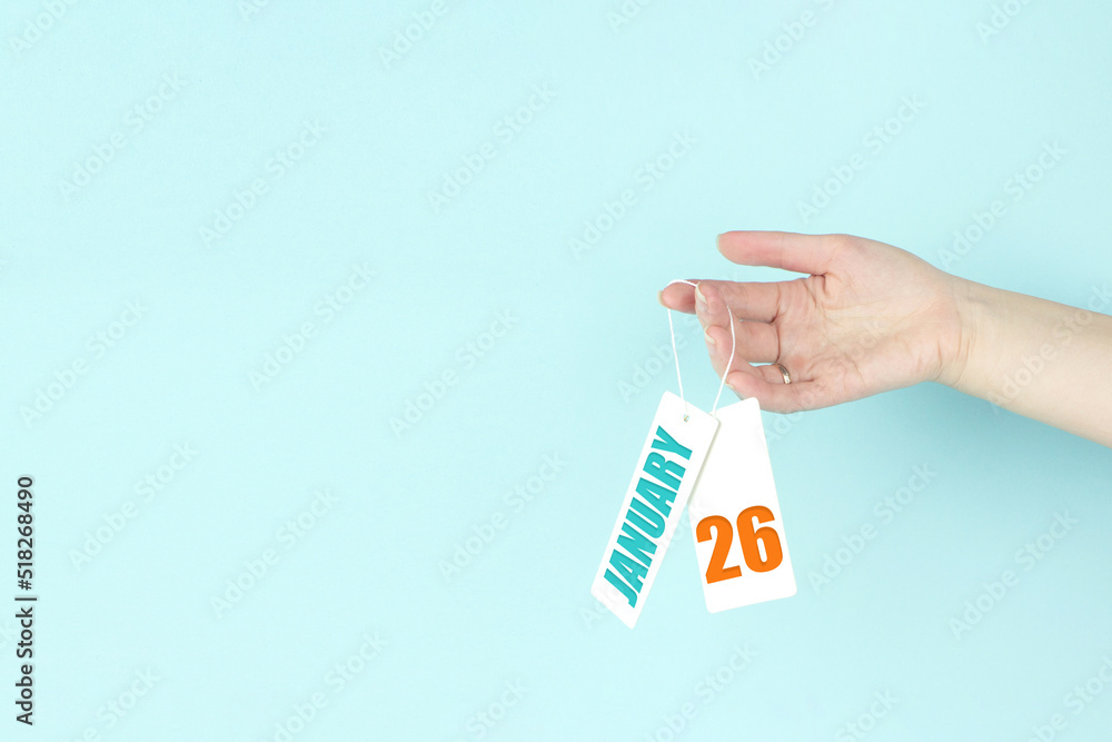 January 26th. Day 26 of month, Calendar date. Hand hold price tag with calendar date on blue background. Winter month, day of the year concept. January 26th. Day 26 of month, Calendar date. Hand hold price tag with calendar date on blue background. Winter month, day of the year concept.