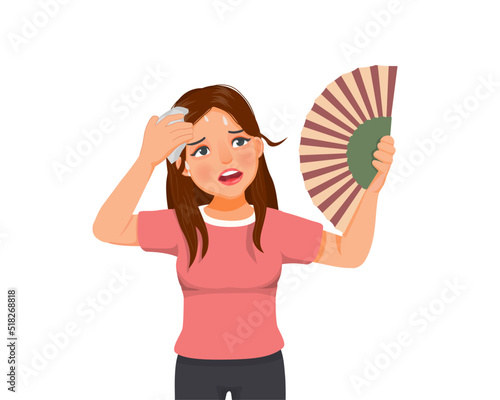 Beautiful young woman suffering heat wave stoke in very hot weather using hand fan and tissue to dry sweat
