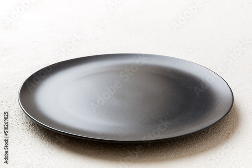 Perspective view of empty black plate on cement background. Empty space for your design