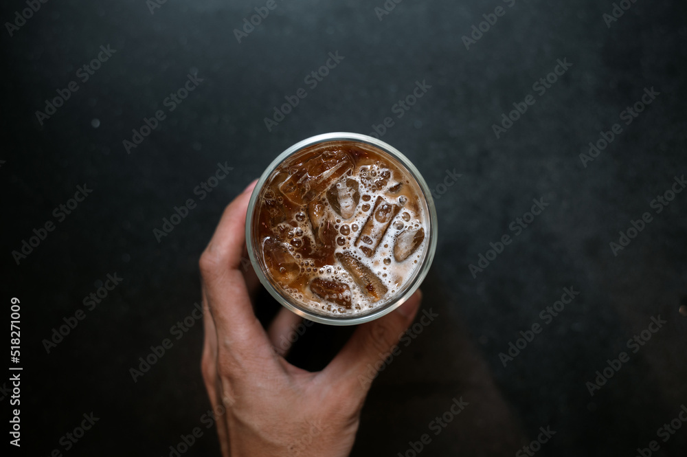 Fototapeta premium hand holding a take-out iced coffee on black table