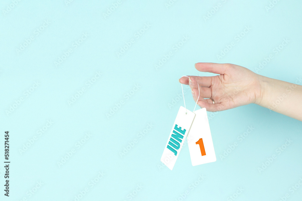 June 1st . Day 1 of month, Calendar date. Hand hold price tag with calendar date on blue background. Summer month, day of the year concept. June 1st . Day 1 of month, Calendar date. Hand hold price tag with calendar date on blue background. Summer month, day of the year concept.