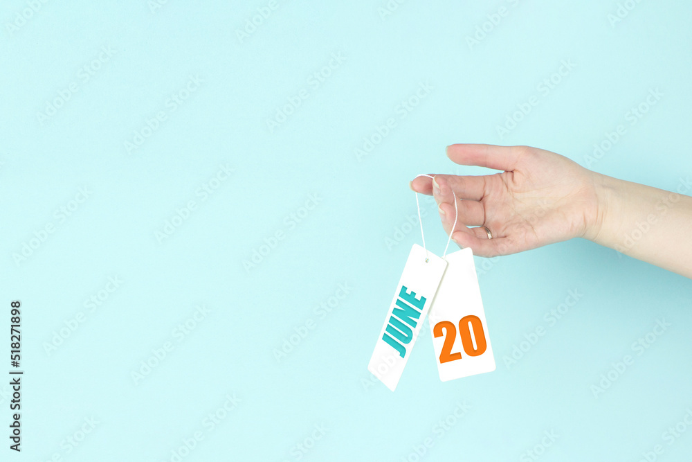June 20th. Day 20 of month, Calendar date. Hand hold price tag with calendar date on blue background. Summer month, day of the year concept. June 20th. Day 20 of month, Calendar date. Hand hold price tag with calendar date on blue background. Summer month, day of the year concept.