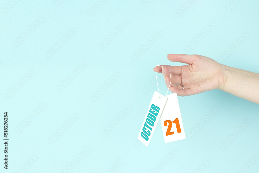 October 21st . Day 21 of month, Calendar date. Hand hold price tag with calendar date on blue background. Autumn month, day of the year concept. October 21st . Day 21 of month, Calendar date. Hand hold price tag with calendar date on blue background. Autumn month, day of the year concept.