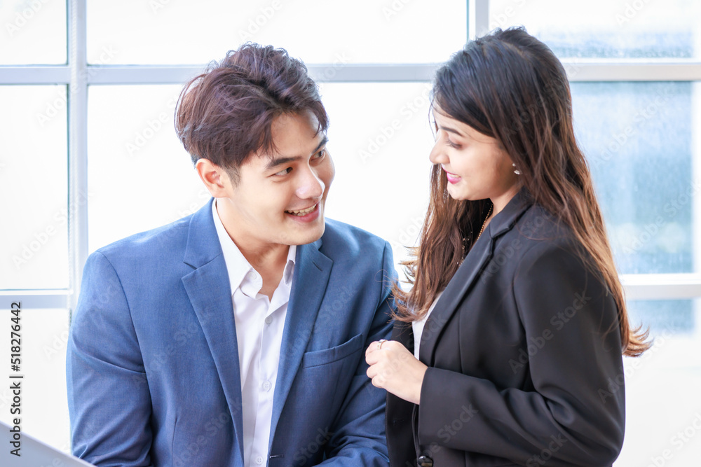 Asian young professional businessman employee in formal suit holding touchscreen tablet computer showing presenting discussing with female businesswoman colleague in company office corridor hallway Asian young professional businessman employee in formal suit holding touchscreen tablet computer showing presenting discussing with female businesswoman colleague in company office corridor hallway