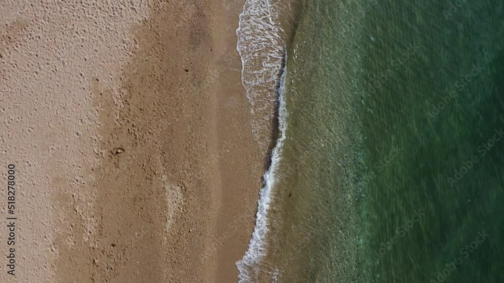 Beautiful remote beach with crystal clear water, aerial view. Untouched nature and hidden sandy beach with seagulls. Motion blur on small waves. Holiday, vacation and travel concept. Nobody