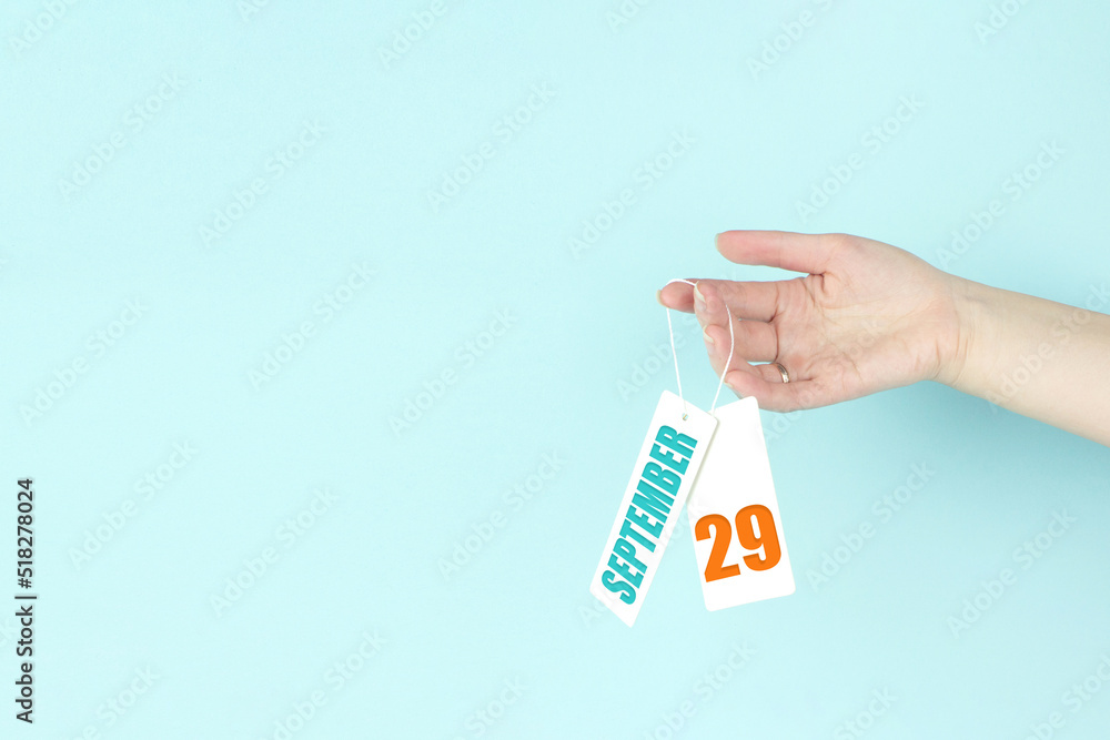 September 29th. Day 29 of month, Calendar date. Hand hold price tag with calendar date on blue background. Autumn month, day of the year concept. September 29th. Day 29 of month, Calendar date. Hand hold price tag with calendar date on blue background. Autumn month, day of the year concept.