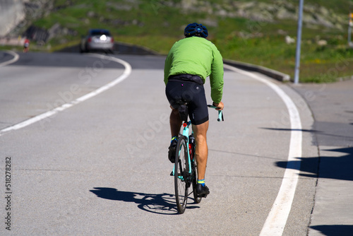 Man on racing bicycle at summit of Gotthard Pass on a sunny summer day. Photo taken June 25th, 2022, Gotthard Pass, Switzerland.