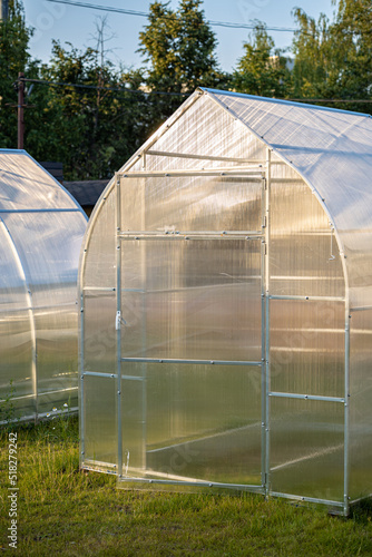 a small plastic greenhouse stands on the lawn