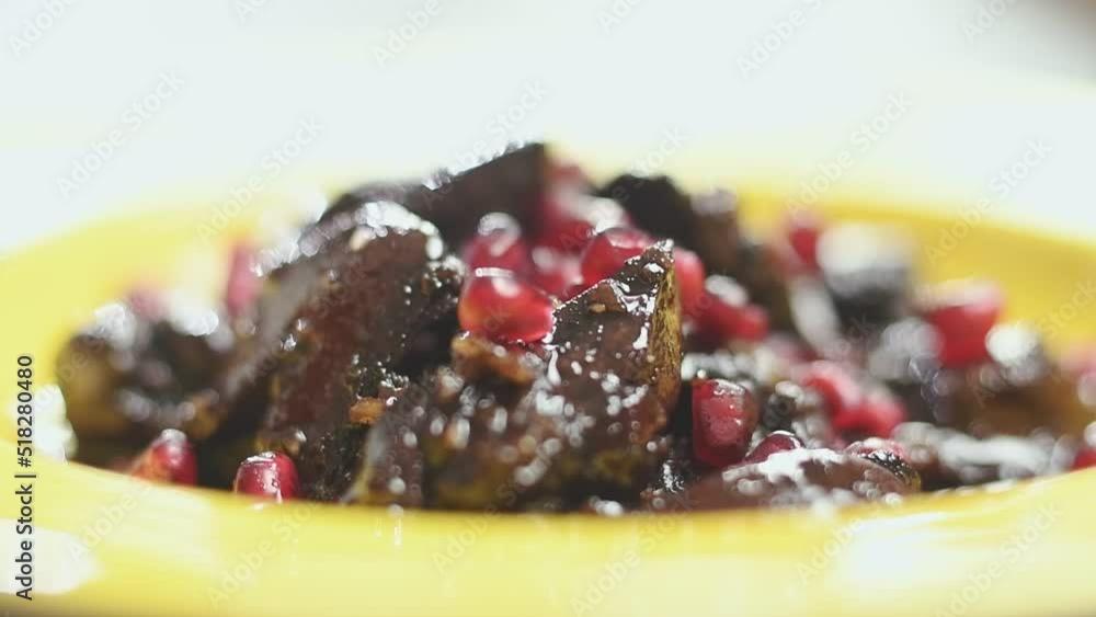 Juicy grains of pomegranate are falling on chicken livers, served on a plate. Juicy grains of pomegranate are falling on chicken livers, served on a plate.