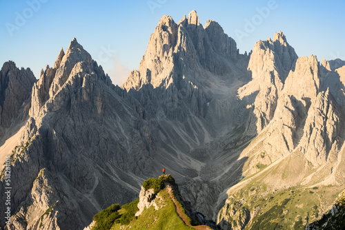 Stunning view of a tourist on the top of a hill enjoying the view of the Cadini di Misurina during sunrise. Cadini di Misurina is a group of mountains located in the Dolomites, Italy. photo