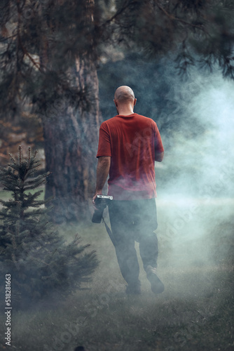 unrecognizable man holding a camera in front of a path in a forest, nature travel and hiking concept.