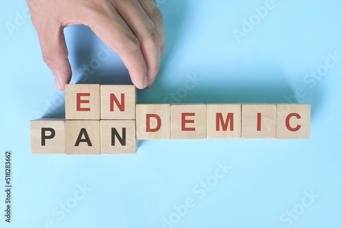 Hand changing word pandemic to endemic in wooden blocks. Covid-19 transition from pandemic to endemic concept. photo