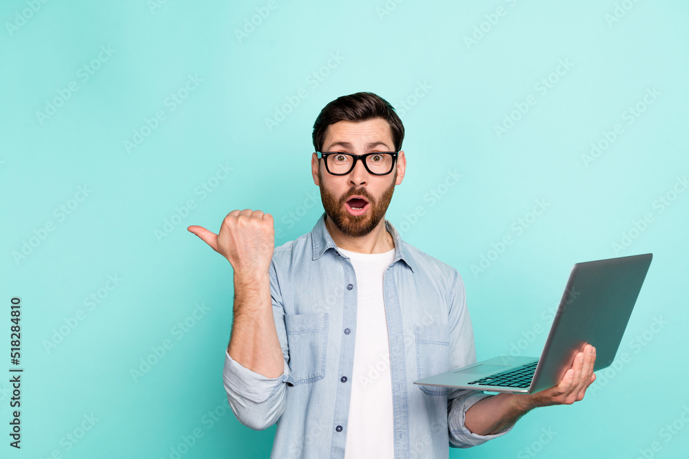 Photo of impressed marketer guy use netbook search ads point empty space wear denim shirt isolated teal color background Photo of impressed marketer guy use netbook search ads point empty space wear denim shirt isolated teal color background