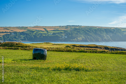 black shrink wrap waterproof covered bale of hay on a coastal farmers field photo