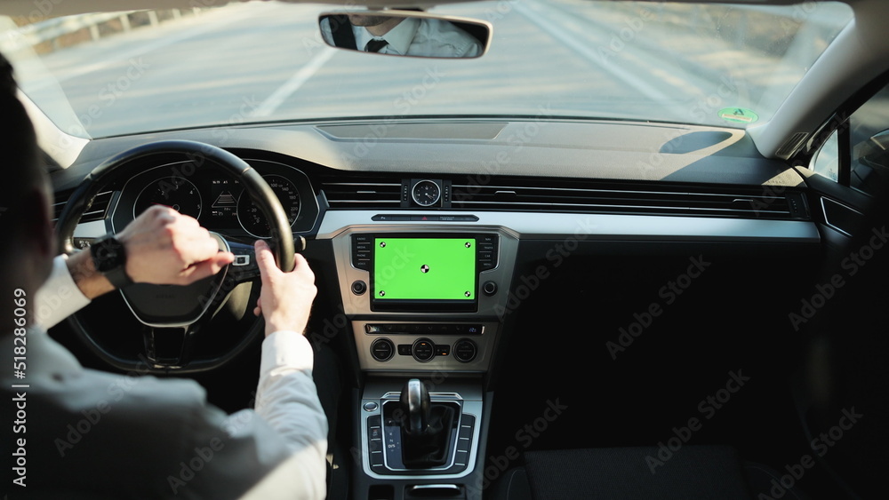 Back view of classic casual businessman in white shirt using smart watch on his hands while driving a car with greenscreen mock-up display dashboard service menu application. Navigation. Map. Driver. Back view of classic casual businessman in white shirt using smart watch on his hands while driving a car with greenscreen mock-up display dashboard service menu application. Navigation. Map. Driver.