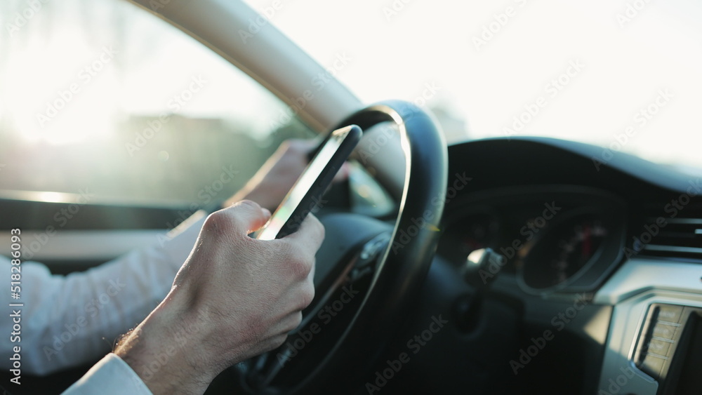 Close-up hands of unrecognizable man typing online message using mobile phone while sitting at car. Closeup view of businessman using phone in auto. Accident insurance. Chatting driver Close-up hands of unrecognizable man typing online message using mobile phone while sitting at car. Closeup view of businessman using phone in auto. Accident insurance. Chatting driver