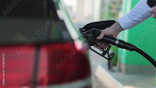 Unrecognizable businessman refueling car from gas station. Senior is refueling car at sunset. Caucasian businessman filling benzine gasoline fuel in car at gas station. Petrol prices concept