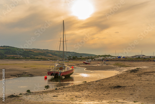 yacht beached on the banks of the river Teifi at Poppit sands and patch ne Cardigan Ceredigion Wales  at sunset golden hour photo
