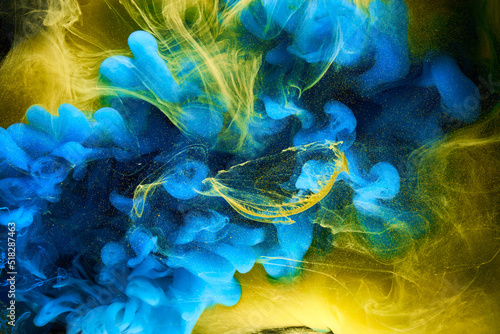 Liquid fluid art abstract background. Blue yellow dancing acrylic paints underwater, ocean space smoke