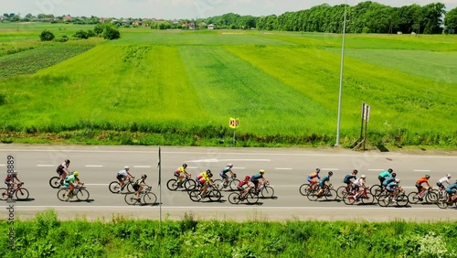 Bicycle racing on the highway. A peloton of cyclists moves against the background of green nature.