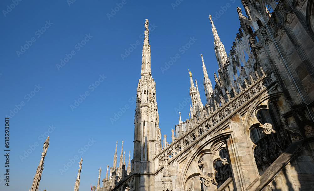 Architecture details from the rooftop of Milan Cathedral (Italian Duomo di Milano) in a blue sky sunny day. Travel landmarks of Italy.