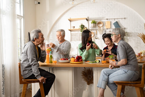 Group of Asian elder people friends making vegetables salad and fruit juice with her daughter in kitchen at home.concept of Group asia senior people Healthy eating,colorful fruits and vegetables.
