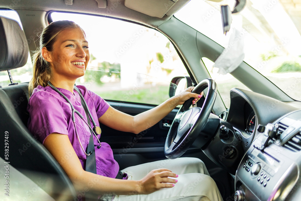 Caucasian female doctor driving her car. Young smiling nurse driving home after a day