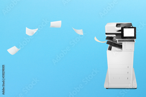 Fotografia Professional office copier with flying papers on blue background