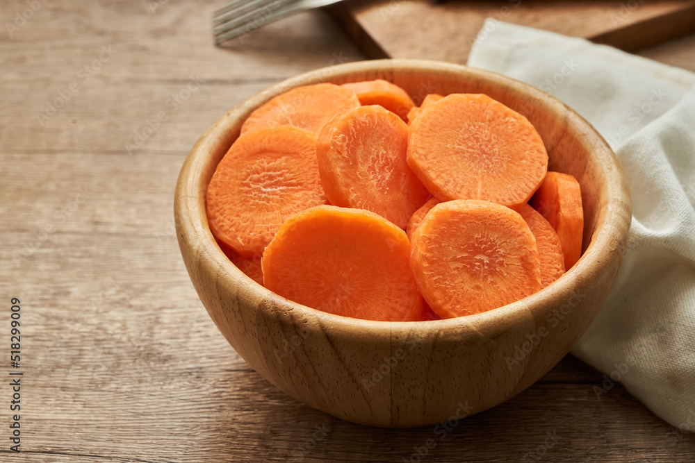 chop round carrot on a wooden bowl on wood table background chop round carrot on a wooden bowl on wood table background