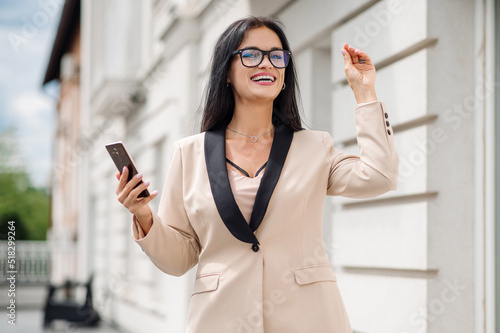 Happy business woman dressed in suit holding a cellphone ont the hotel terrace