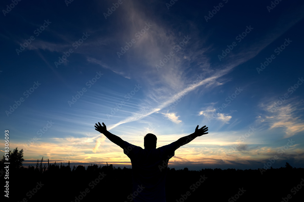 Silhouette of man with arms raised up and beautiful sky. Element of design. Summer sunset.