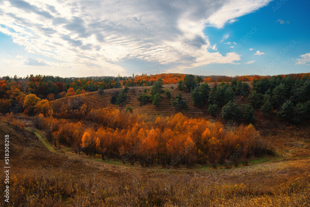 Bright autumn sunset over trees on hills in Ukraine