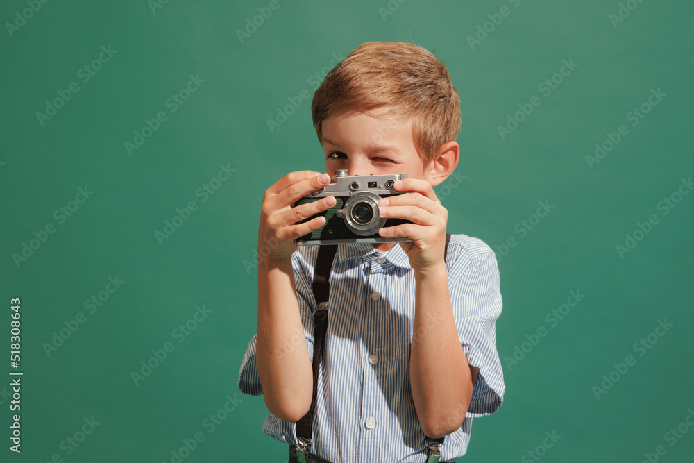 One preschool boy, kid wearing retro style outfit isolated on dark green background. Concept of emotions, facial expression, fashion, vintage and ad. One preschool boy, kid wearing retro style outfit isolated on dark green background. Concept of emotions, facial expression, fashion, vintage and ad.