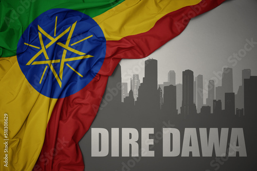 Foto abstract silhouette of the city with text Dire Dawa near waving colorful national flag of ethiopia on a gray background