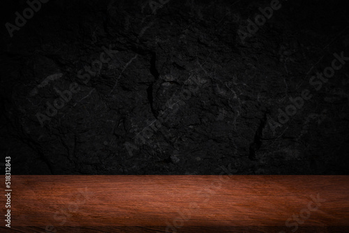 Empty space on wooden table for displaying food or beverage products with blurred black wall background.
