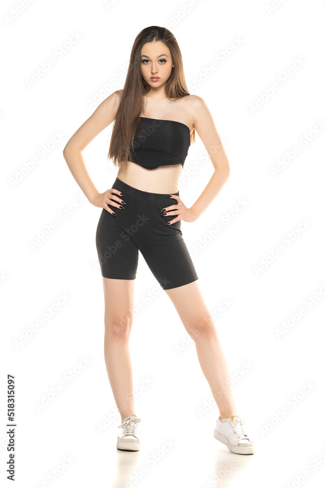 Young woman in black shorts and top posing in the studio on white background Young woman in black shorts and top posing in the studio on white background