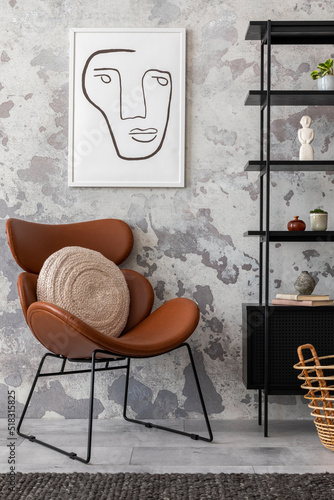 The stylish composition of wabi sabi interior with mock up poster, black rack, brown armchair with pillow and personal accesoories. Grey concrete wall. Home decor. Template. photo