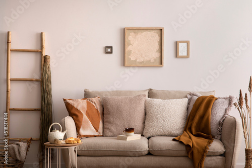 The stylish composition of living room interior with beige sofa with brown carpet  pillow  plaid  coffee table and personal accessories. beige wall with mock up poster. Home decor. Template.