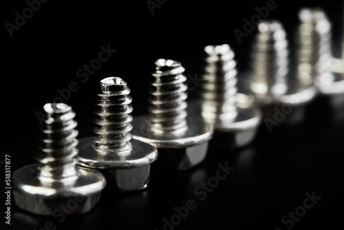 A row of Small bolts for computer equipment and computer assembly on black background
