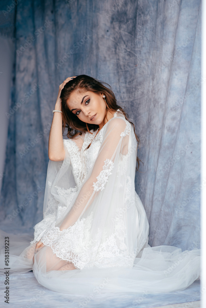 Fototapeta premium Brunette bride in white luxury wedding dress looking at the camera at loft studio