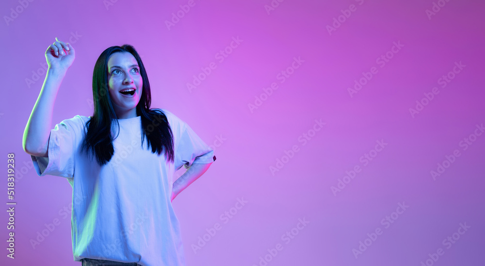 Portrait of adorable girl, young woman with long glossy dark hair isolated on purple background in neon light. Concept of beauty, art, fashion, emotions