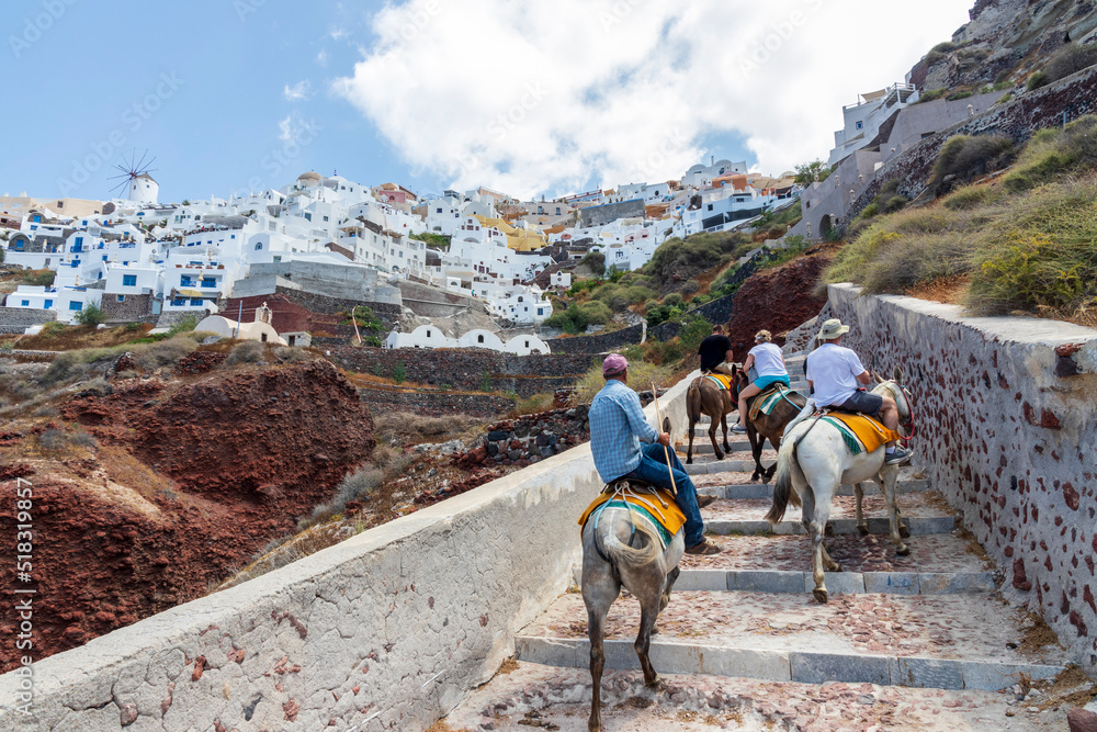 Fototapeta premium Santorin Greece. 06-11-2022. Tourists climbing stairs on horses at Oia village at Santorin Island. Cyclades Island. Greece.