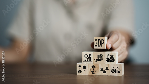 GDP, symbol of gross domestic product Businessman holding a wooden block with an icon saying 'GDP' copy space. Business and GDP growth. Gross domestic product concept. photo
