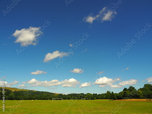 Sports ground with green grass and blue sky with clouds on sunny day in Ballincollig Park, Cork, Ireland