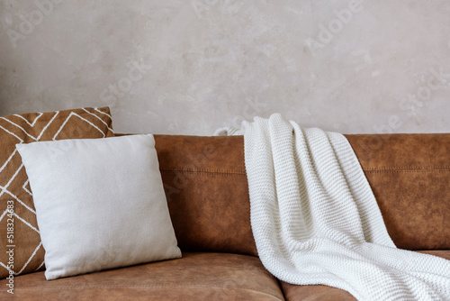 Closeup of eco leather sofa with pillows and white plaid